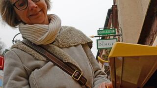 Marlise Teicke vom Frauenverein Wertheim wirft eine der Aktions-Postkarten für den Erhalt der Rotkreuzklinik Wertheim in den Briefkasten am Rathaus.