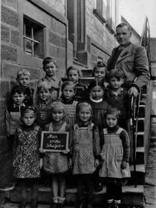 Einschulung im Jahr 1949 mit Schulleiter Karl Kraus (linkes Bild). Schüler und Lehrer der Volksschule Distelhausen im Jahr 1909 vor der St. Markus Kirche direkt neben der Schule (mittleres Bild). Blick auf die Schule in Distelhausen im Jahr 1949.