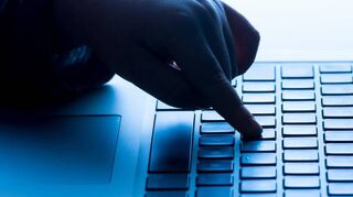 Ein Täter nutzt die Tastatur eines Laptops für seine kriminellen Aktivitäten.