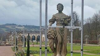 Schloss und Schlossgarten Weikersheim: Die Sandsteinfiguren im Lustgarten (im Hintergrund die Orangerie) sind „ausgehaust“ und die Blumen stehen in Blüte.