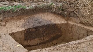 Die dunklen Verfärbungen der Erde zeigen den Archäologen deutlich die Umrisse der keltischen Abfallgrube.