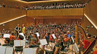 Volles Haus mit „La Ola“ und ganz viel Applaus:Tobias Krell, die Reutlinger Philharmoniker (einmal nicht im schwarzen Anzug, sondern in Fußball-Shirts) mit Dirigent und „Schiedsrichter“ Hermes Helfricht.