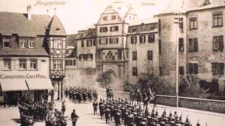 Im Ersten Weltkrieg war Mergentheim Garnison und beherbergte 3000 Soldaten. Das Schloss diente als Kaserne. Das Bild zeigt eine Marschparade auf dem Burgplatz im Kriegsjahr 1914.