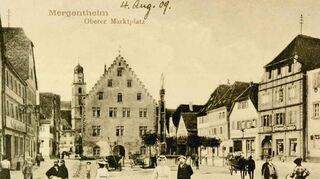 Eine historische Aufnahme: 1909 gehörte der Obere Markt den Spaziergängern (unser Bild). Auf einem Bild aus dem Jahr 1942 ist nur ein beschaulicher Leiterwagen am Marienbrunnen zu sehen. Aber schon 15 Jahre später zeigt eine Fotografie den mit Autos zugeparkten Platz.