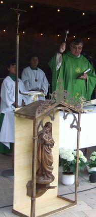 Pfarrer Pater Joachim Seraphin segnet Dorfmitte und Menschen.