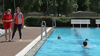 Trainerinen der DLRG beobachten Im Bestenheider Freibad die Prüflinge bei der Abnahme von Schwimmabzeichen.