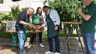 Altheims Ortsvorsteher Hubert Mühling und Walldürns Bürgermeister Meikel Dörr packen zusammen an beim Bieranstich, um das Jubiläumswochenende in Altheim zu eröffnen.