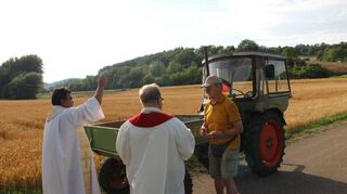Die Priester Damian Samulski (Mitte) und Arul Arockiasamy segneten nach der Andacht in der Liebfrauenbrunnkapelle in Werbach Fahrzeuge, darunter auch vier alte Traktoren.