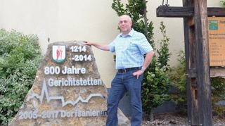 Karl Schretzmann an der Gedenktafel zu „800 Jahre Gerichtstetten“. Mit den Heimattagen 2015 nahm sein ehrenamtliches Engagement in seinem Heimatort Fahrt auf. Jetzt ist der 56-Jährige der neue Ortsvorsteher in Hardheims zweitgrößtem Ortsteil.