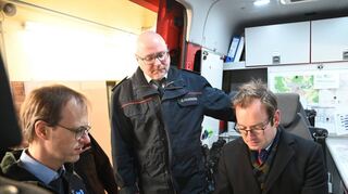 Christoph Graf-Hadry (von links) von der Firma Leicht Funktechnik, Kreisbrandmeister Andreas Geyer und Erster Landesbeamter Florian Busch betrachten ein Digitalfunkgerät in einem Feuerwehrfahrzeug. Der Schwerpunkt der Fördersumme liegt auf den Endgeräten, die für die Umstellung auf den Digitalfunk benötigt werden.
