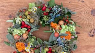 Ein Herbstkranz aus Gartenblumen, Blättern und Früchten.