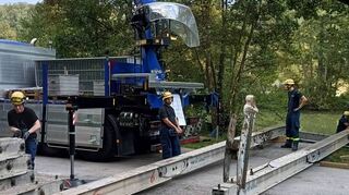 Mit Hilfe eines Krans installieren die ehrenamtlichen Kräfte des Technischen Hilfswerks Wertheim das Grundgerüst der schwimmenden Brücke.