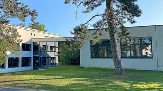 Blick auf die Westfassade des Gymnasiums: Das Hallenbad liegt von außen nicht sichtbar im Baukörper. Der untere Raum links war ein Klassenzimmer (u. a. Kunst); er gehört künftig zum Bad.