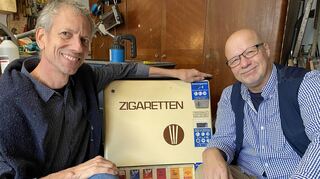 Zweites Leben für einen alten Zigarettenautomat aus Wertheim: Statt „Roth-Händle“ kann man aus ihm (nach künstlerischer Umgestaltung) Kunstwerke ziehen, die ins Schachtelformat hineinpassen. Lothar Lempp (links) und Michael Blümel suchen einen Platz zum Aufhängen in der Bad Mergentheimer Altstadt.