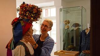 Ursula Wehner befestigt in der neuen Textilausstellung des Grafschaftsmuseums einen mit einer Brautkrone geschmückten Kopf auf einer Puppe.
