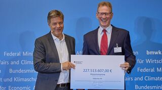Minister Robert Habeck (l.) übergibt einen Klimaschutzvertrag an Hans-Peter Gai, Vorstandsmitglied der Südzucker AG.