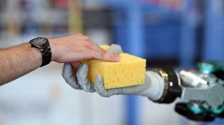 Digitalisierung schreitet voran: Beim Karlsruher Institut für Technologie (KIT) wird ein Roboter gezeigt, der einen Schwamm an einen Menschen übergibt.