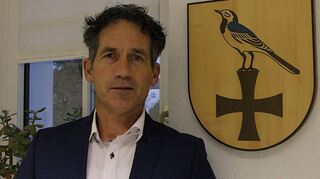 Ortsvorsteher Rainer Blank im Löffelstelzer Rathaus neben dem ehemaligen Wappen der Gemeinde: Schwarzes Deutschordenskreuz kombiniert mit einer blauen Bachstelze.