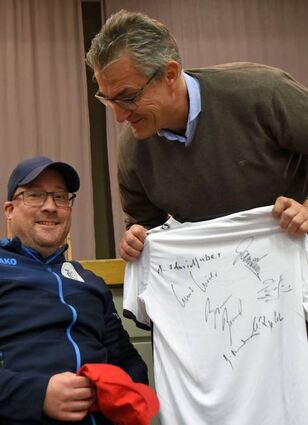 Daniel Hofmann (links), der im Rollstuhl sitzt, freut sich sichtlich über das unterschriebene Trikot, das ihm Knut Kircher überreichte.