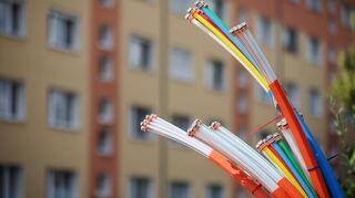 Aus dem Sockel eines Schaltschranks ragen Glasfaserkabel heraus. In der Region Odenwald-Tauber stockt der Breitbandausbau weiterhin.