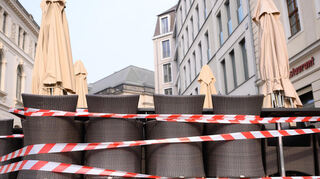Der erste Corona-Lockdown in Deutschland ist genau fünf Jahre her. Das Beispielbild zeigt ein Absperrband, das Tische und Stühle vor einem geschlossenen Restaurant umgibt.