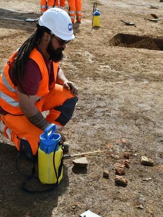 Grabungsleiter Laurin Scheiderer begutachtet die Fundstücke. Darunter ist auch das Fragment eines Steins zum Mahlen von Mehl.