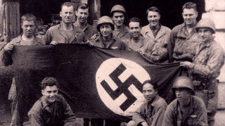 Soldaten des 1. Bataiilons des 253. Infanterie-Regiments mit einer erbeuteten Hakenkreuzfahne vor dem Badischen Hof.