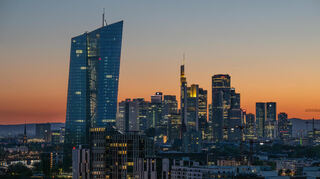 Die Lichter der Bankentürme von Frankfurt leuchten in der hereinbrechenden Dunkelheit, die EZB (l.) dominiert die Skyline.