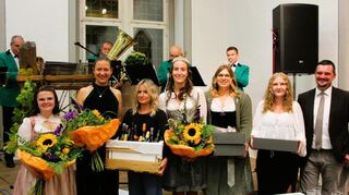 Die Gewinner des Erlkönigs zusammen mit Bürgermeisterin Heidrun Beck sowie den beiden Schüpfer Weinhohheiten Anna-Lena Graf (links), Annalena Schindler (Vierte von links) und Ortsvorsteher Stefan Graf. Im Hintergrund die Umpfertäler Musikanten