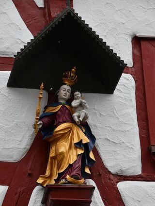 Die Madonna am Hohen Haus in Königshofen stellt eine "Patronin Bavariae" dar, verbunden mit den Insignien der Jungfrau Maria.