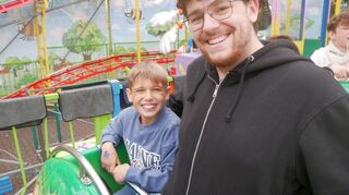 Erzieher Tim Weber mit seinem Schützling Silas in der Achterbahn auf dem Schützenmarkt.