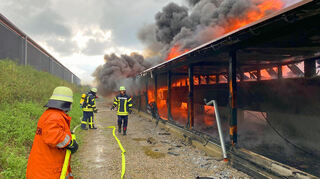 Von der Hangseite aus versuchen Feuerwehrleute einen lichterloh brennenden Stall-Teil abzulöschen und das Übergreifen der Flammen zu verhindern.