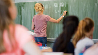 Eine Lehrerin schreibt an einer Schultafel im Mathematikunterricht einer 8. Klasse an einer Integrierten Gesamtschule.