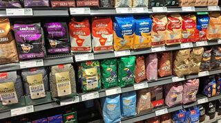 Packungen mit Bohnenkaffee stehen in den Regalen eines Supermarktes.