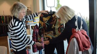 Brigitte Fischer und Doris Knörzer drapieren eine Bluse auf eine Schaufensterpuppe.
