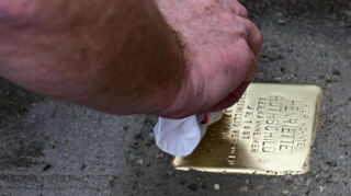 Vorsichtig wurde der frisch verlegte Stolperstein zur Erinnerung an Henriette Rothschild von Gunter Demnig gesäubert.
