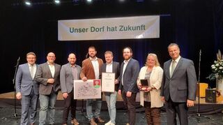 Über die Goldmedaille für Rauenberg beim Landeswettbewerb Unser Dorf hat Zukunft freuen sich (von links) Landrat Christoph Schauder, Bürgermeister Roger Henning, die Ortschaftsräte Helmut Helmker, Holger Weis, Thorsten Ullrich und Julian Ullrich sowie Ortsvorsteherin Margarete Schmidt. Die Auszeichnung wurde von Minister Peter Hauk (rechts) überreicht.