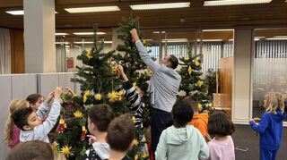 Die Schülerinnen und Schüler der Grundschule am Schloss aus Tauberbischofsheim schmücken die Weihnachtsbäume in der Sparkassen Kundenhalle.